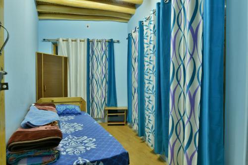 a bedroom with blue walls and a bed in a room at Lhachik Guest House in Leh