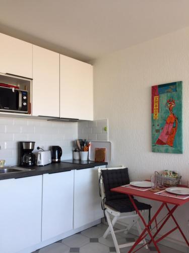 d'une cuisine avec une table, des armoires blanches et une table avec une table. dans l'établissement appartement Terrasse magnifique vue mer et yachts, à Antibes