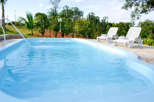 a pool with two chairs and a water fountain at Recanto Vovô Octávio - Refúgio Encantador em meio a Natureza in Olímpia