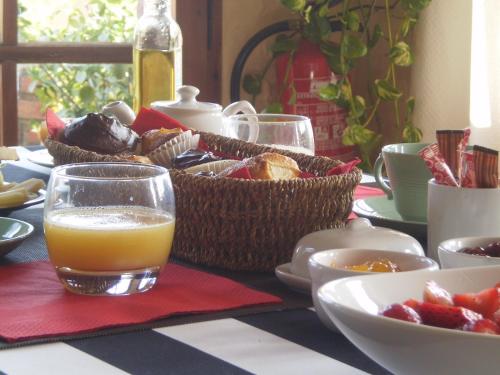 Una mesa cubierta con cestas de comida y un vaso de jugo de naranja. en Casa Matilda Bed and Breakfast, en Corçà