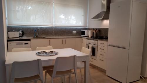 een witte keuken met een witte tafel en stoelen bij Apartament Santa Marina in Platja  d'Aro