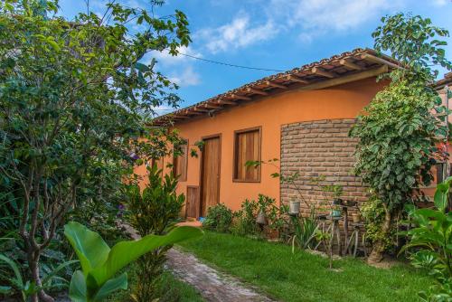 uma pequena casa laranja com um jardim em frente em Casas do San Caraíva - Turma em Caraíva