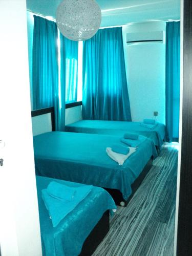 a blue room with three beds and a chandelier at Деси Къща за гости 1 in Chernomorets