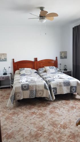 Un dormitorio con dos camas y un ventilador de techo. en Casa Makuki, en Playa Honda