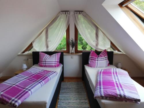 2 Betten in einem Dachzimmer mit Fenstern in der Unterkunft Fa Haack in Neuried