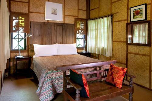 a bedroom with a bed and a bench and windows at Mae Nai Gardens in Ban Mae Mae