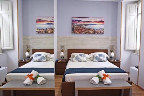 a bedroom with two beds and two paintings on the wall at La Dimora Luca Giordano in Naples