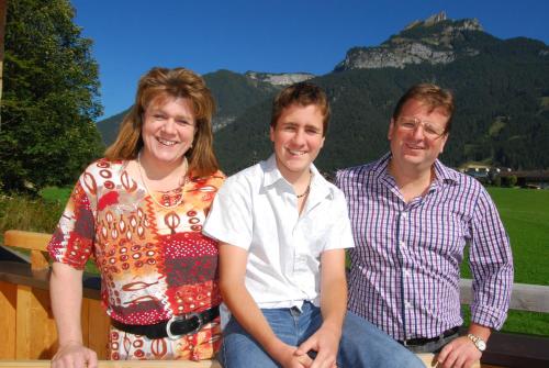 three people sitting on a bench in front of a mountain at Achenseer Hüttendörfl in Maurach