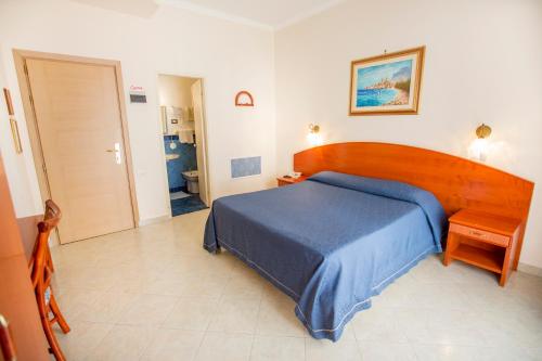 a bedroom with a blue bed and a wooden headboard at Hotel Mediterraneo in Cefalù