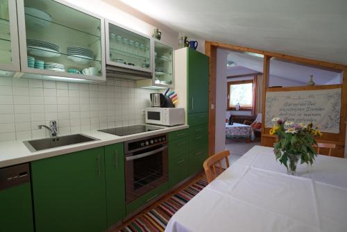 cocina con armarios verdes y mesa con mantel blanco en Haus Waltraut, en Ramsau am Dachstein