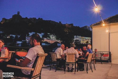 a group of people sitting at tables on a patio at night at Friends' Guesthouse & Hostel in Gjirokastër