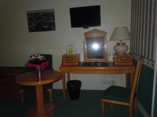 a room with a desk with a tv and a table with a chair at La Croix Blanche in Montrichard