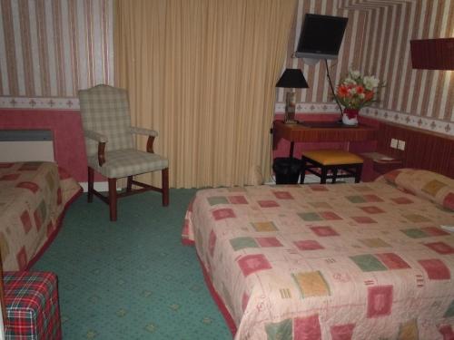 a hotel room with two beds and a chair at La Croix Blanche in Montrichard
