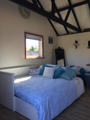 a bedroom with a large bed with blue sheets and a window at Saving Grace with private hot tub in Bawdeswell
