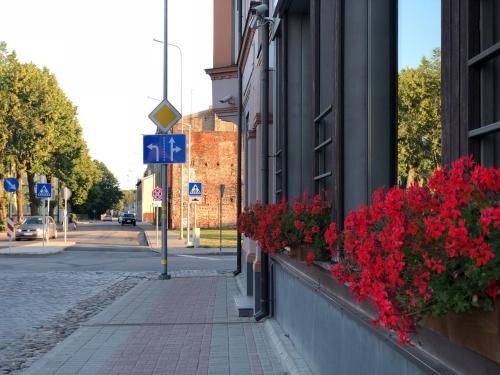 a street with red flowers on the side of a building at Hotel Kolumbs in Liepāja