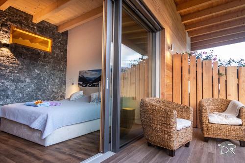 a bedroom with a bed and two chairs on a balcony at Casa de Fiemme in Tesero