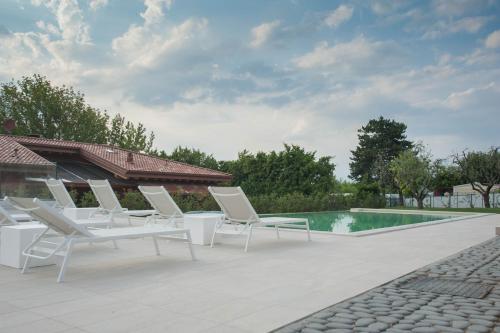 a group of white lounge chairs next to a swimming pool at Italianflat - Maison du Lac in Lazise