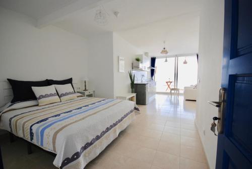 a white bedroom with a bed and a living room at Marine Lovers - Jacuzzi Fuerteventura in Gran Tarajal