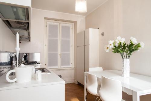 a white kitchen with a vase of flowers on a counter at Milan Royal Suites - Centro in Milan