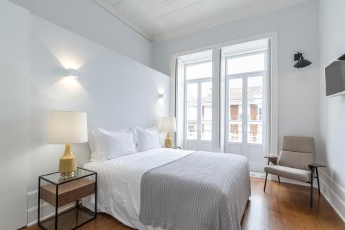 um quarto branco com uma cama e uma cadeira em AQ 188 Guest House em Coimbra