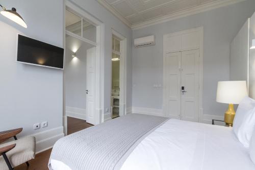 a white bedroom with a white bed and a desk at AQ 188 Guest House in Coimbra