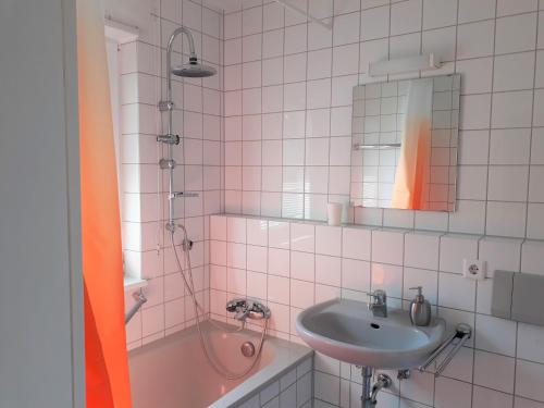 ein rosa gefliestes Bad mit einem Waschbecken und einer Dusche in der Unterkunft Apartment Walldorf in Walldorf
