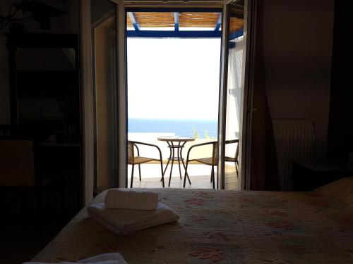 a bedroom with a door open to a view of the ocean at Stella's Houses in Agia Pelagia Kythira