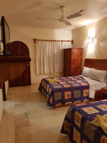a bedroom with two beds and a television in it at Hotel Kootznoowoo in Puerto Escondido