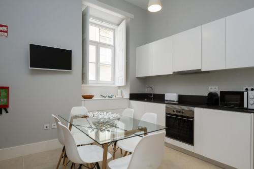 une cuisine avec une table en verre et des placards blancs dans l'établissement AQ 188 Guest House, à Coimbra