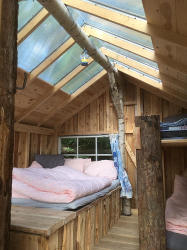 a bed in a wooden cabin with a roof at Treehouse B&B in Rabjerg