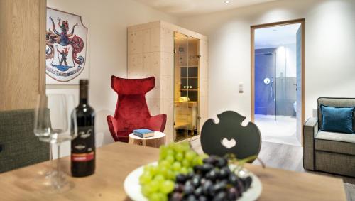 a bottle of wine and grapes on a table in a living room at Hotel Christof in Appiano sulla Strada del Vino