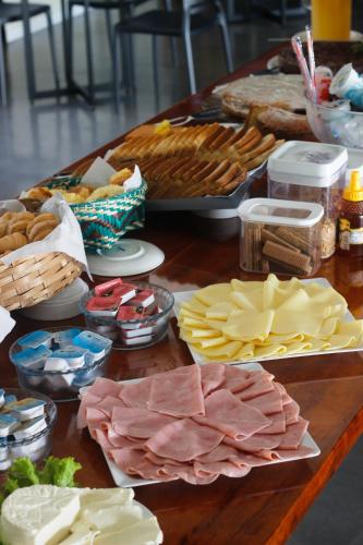 een tafel met verschillende soorten kaas en vlees bij Luz da Lua Pousada in Ubatuba