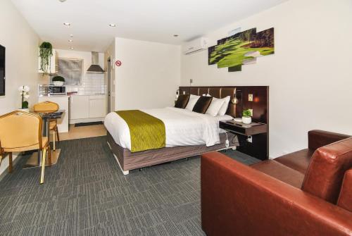 a bedroom with a bed and a couch and a kitchen at Newlands Court Motel in Wellington
