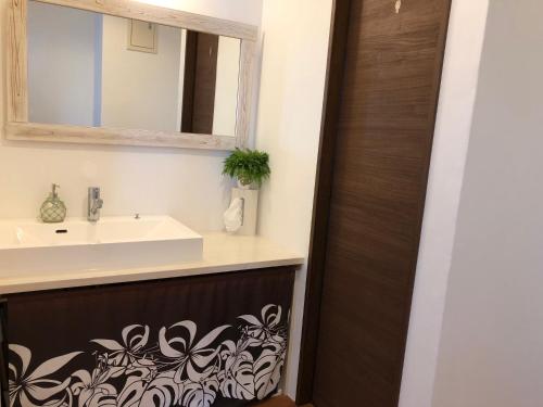 ein Bad mit einem Waschbecken und einem Spiegel in der Unterkunft Guest room Halemakana in Amami