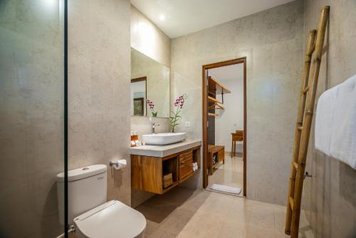 uma casa de banho com um WC, um lavatório e um espelho. em Jati Cottage em Ubud