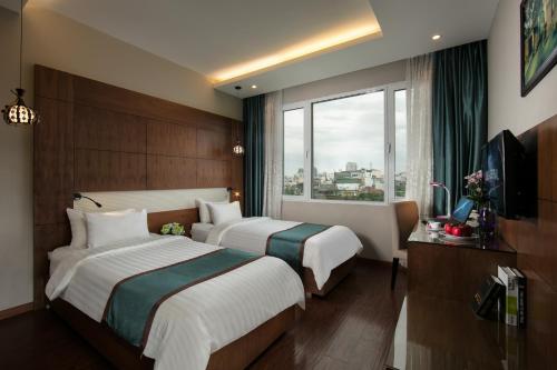 two beds in a hotel room with a window at Bonne Nuit Hotel & Spa Hanoi in Hanoi