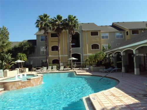 a swimming pool in front of a building with palm trees at NEW 2bed2bath condo - CLEARWATER BEACH - FREE Wi-Fi and Parking in Clearwater