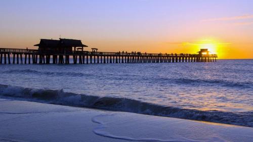 a beach with a pier and the ocean at sunset at NEW 2bed2bath condo - CLEARWATER BEACH - FREE Wi-Fi and Parking in Clearwater