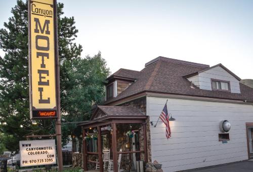 una señal de hotel frente a un edificio con una señal en Canyon Motel en Hot Sulphur Springs