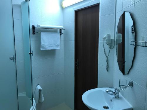a bathroom with a sink and a shower with a mirror at Hotel Shagyn in Astana