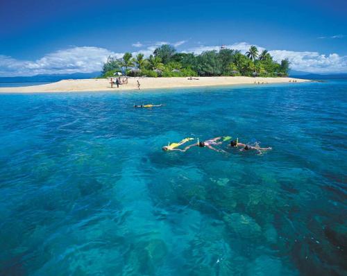 two people swimming in the ocean near a beach at Port Douglas Penthouse Suite in Port Douglas