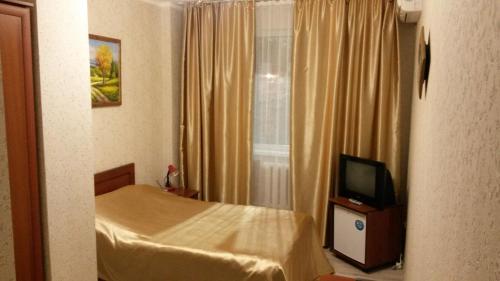 a small bedroom with a bed and a television at Hotel Shagyn in Astana