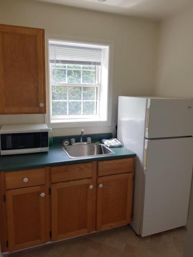 a kitchen with a sink and a white refrigerator at Covered Bridge Inn & Suites in Sussex
