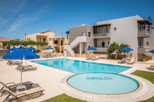 a swimming pool with chairs and umbrellas next to a building at IRINI STALOS Apartments in Stalos