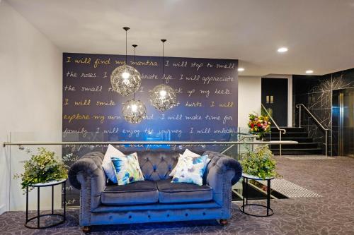 a blue couch in a room with a wall with words at Mantra Albury in Albury
