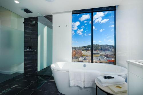 a bathroom with a bath tub and a large window at Mantra Albury in Albury