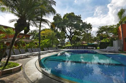 a large swimming pool with lounge chairs and palm trees at Hosteria Las Quintas Hotel Restaurante Bar in Cuernavaca