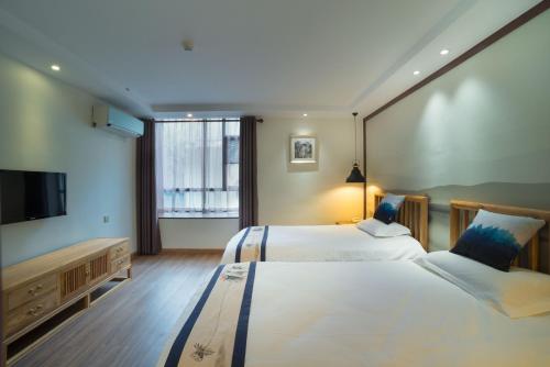 a hotel room with two beds and a flat screen tv at Riverside Inn Guilin Central in Guilin
