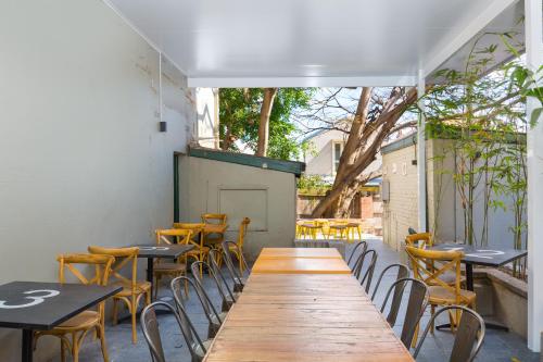 een lange houten tafel en stoelen in een restaurant bij The Village Glebe in Sydney