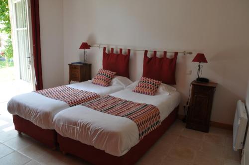 a bedroom with two beds with red pillows on them at Hôtel du Donjon in Aulnay